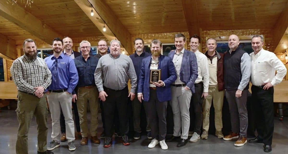 A large group photo at an industry event with a trophy