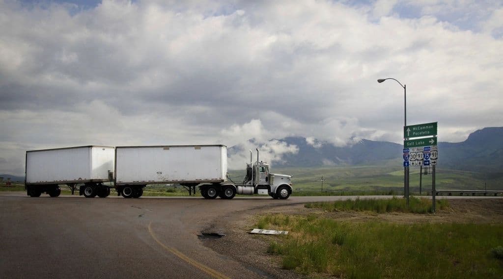 Semi truck hauling two trailers on a mountain highway