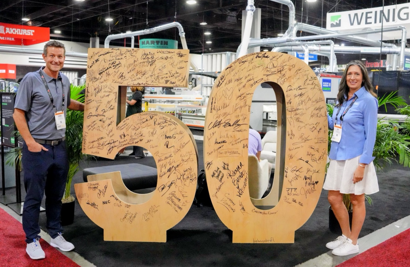 Scarlett team members beside a large 50 sign at the Weinig booth on the IWF show floor