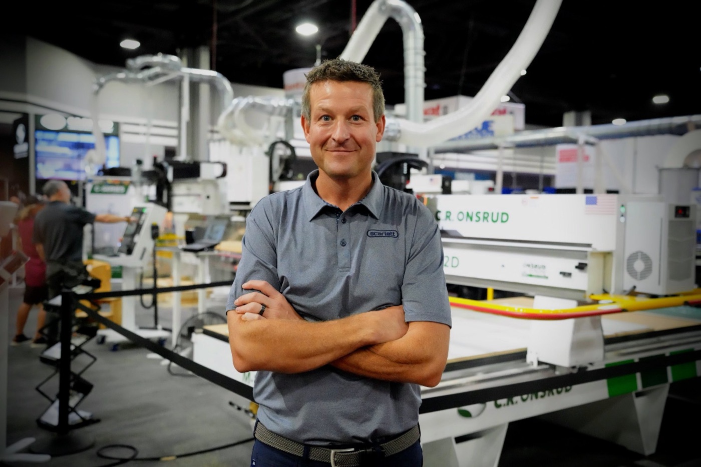 A Scarlett team member beside a machine on the IWF show floor